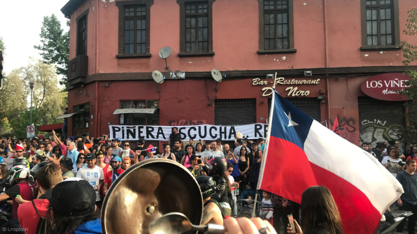 Photograph showing a crowd in protest waving a flag of Chile.