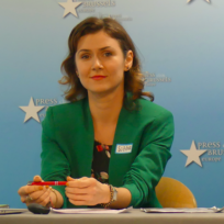 Image of woman in green jacket smiling.