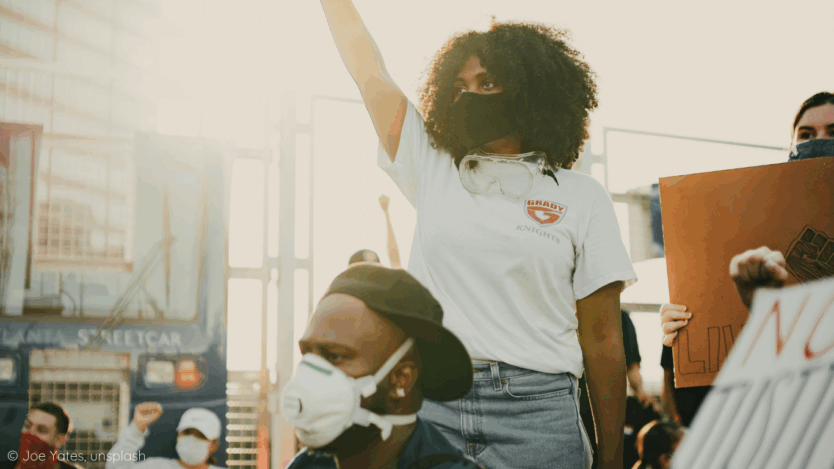 A woman in white t-shirt holds up her fist.